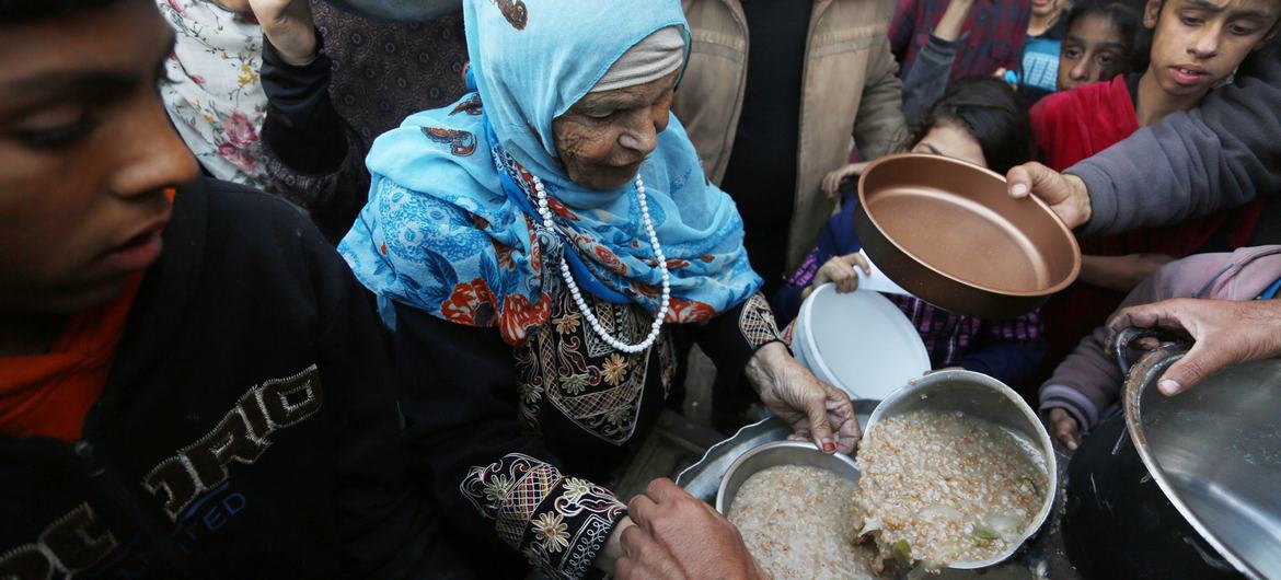 Palestinos deslocados recolhem alimentos num ponto de distribuição perto de uma escola transformada em abrigo em Gaza Palestinos deslocados recolhem alimentos num ponto de distribuição perto de uma escola transformada em abrigo em Gaza