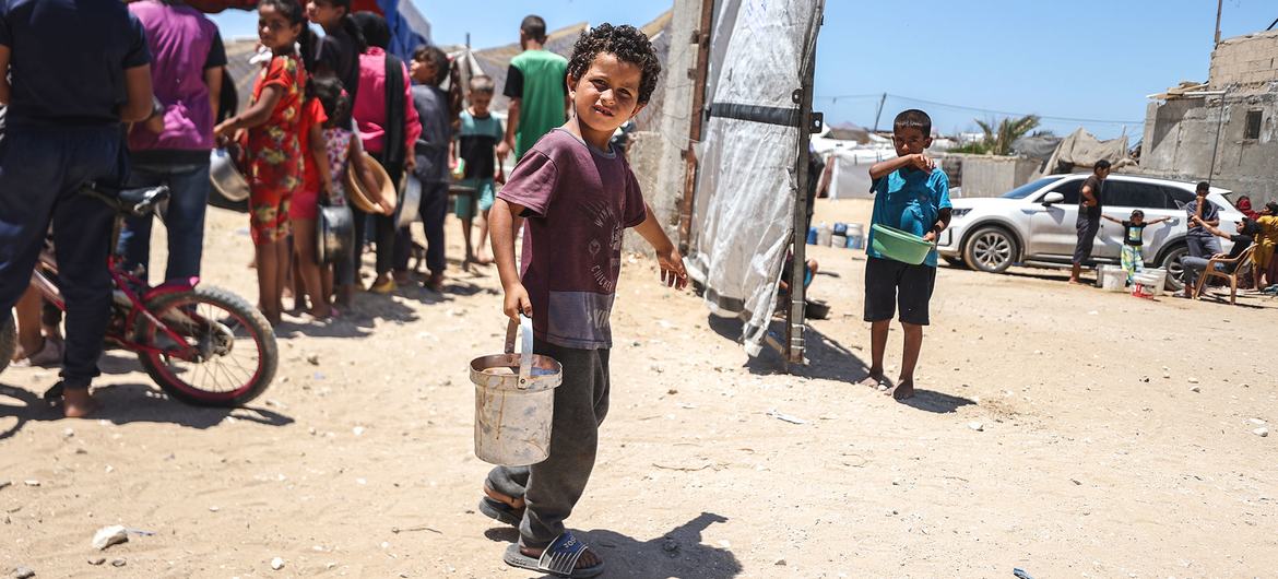 Uma criança recebe comida em uma cozinha apoiada pelo PMA em Khan Younis, Gaza