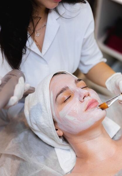 Free Photo | Beautician with a brush applies a white moisturizing mask to the face of a young girl client in a spa beauty salon