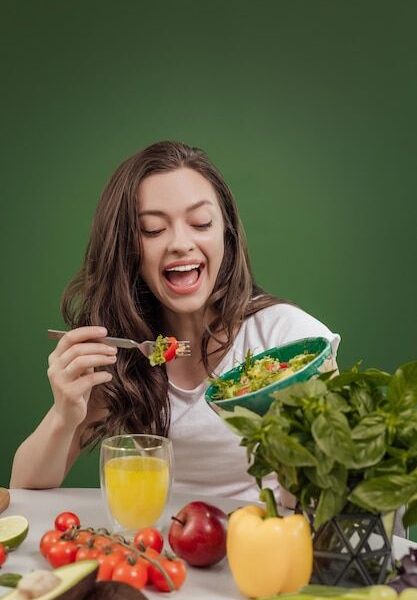 Jovem comendo comida saudável sentada no belo interior com parede verde ao fundo | Foto Premium