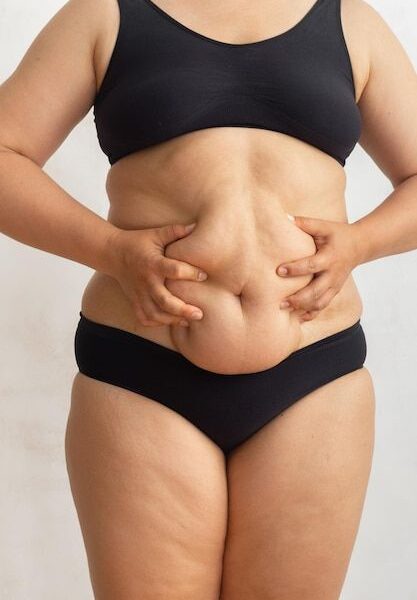Mujer gorda con sobrepeso recortada en bikini negro tocando y apretando el abdomen caído Deshacerse del masaje del vientre colgante | Foto Premium