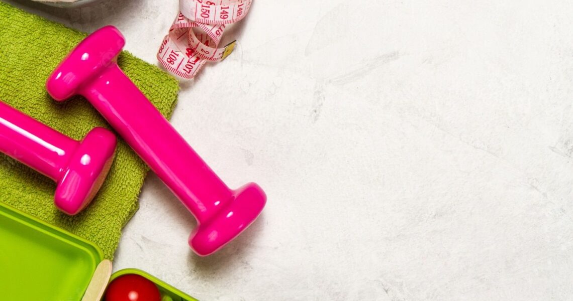 Premium Photo | Pink weights with a green towel and a tape measure